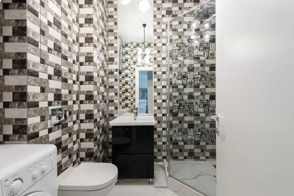 Interior of bright washroom with washing machine near toilet next to shower and sink with tap